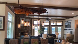 A dining area with a wooden table, upholstered chairs, and pendant lights. - Magnificent Four Bedroom, Two 1/2 Bath luxury, log-sided Harbor North cottage with incredible views of Lake Ouachita. by RedAwning (Mount Ida)