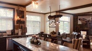 A spacious living area with a large marble island, comfortable seating, and a stone fireplace. - Magnificent Four Bedroom, Two 1/2 Bath luxury, log-sided Harbor North cottage with incredible views of Lake Ouachita. by RedAwning (Mount Ida)
