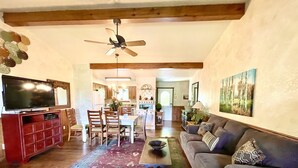 A living room with a television, wooden furniture, a patterned rug, and a ceiling fan. - C8, Two bedroom, two bath log-sided, lake view luxury cottage with hot tub by RedAwning (Mount Ida)