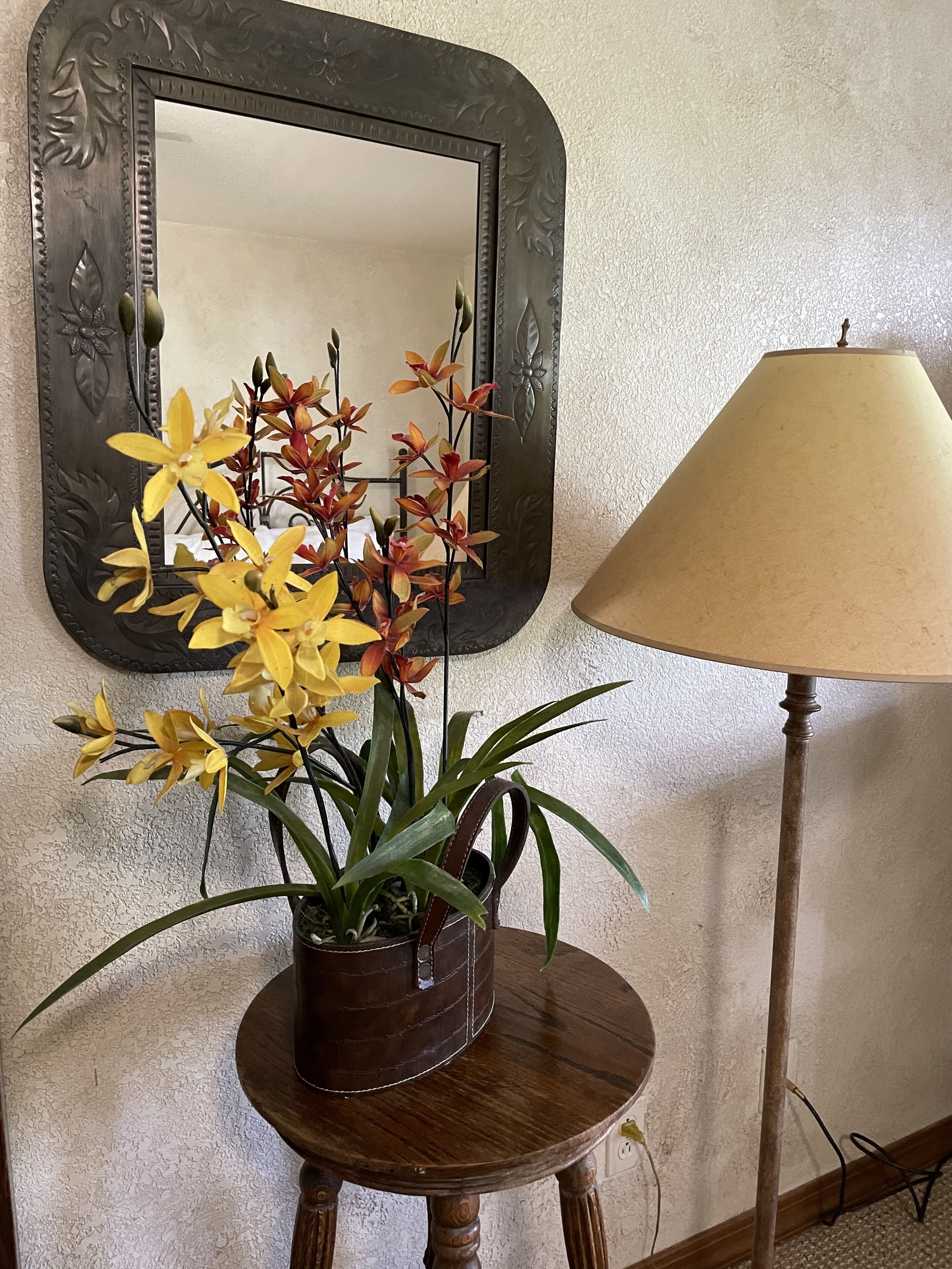 A potted orchid plant on a wooden table with a lamp beside it.