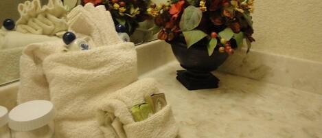 A bathroom with a white towel, a bottle, and a vase with flowers on the counter.