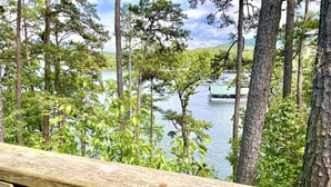 Une terrasse en bois donnant sur un lac, avec des arbres et un quai.