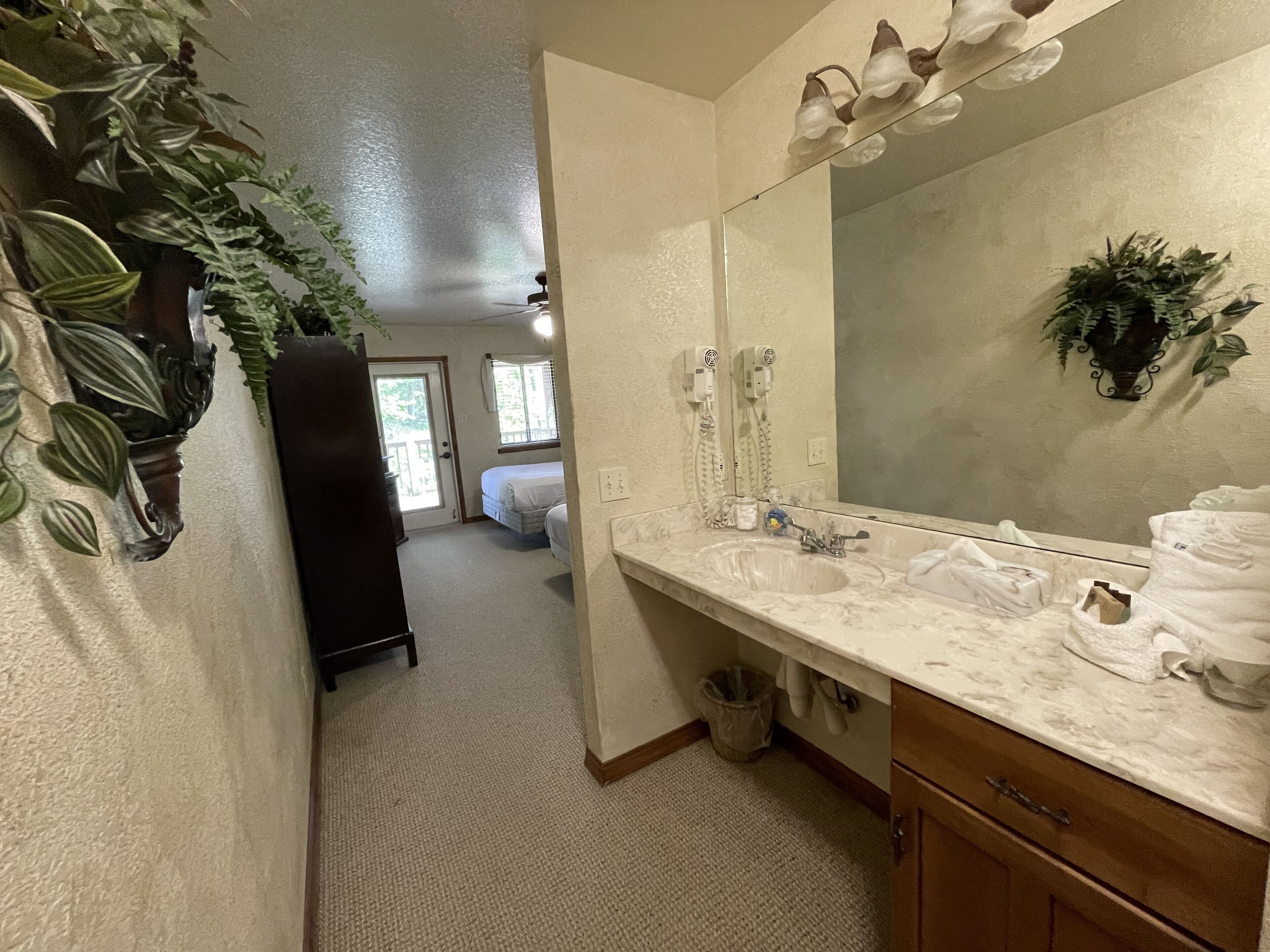 A bathroom with a large mirror, a sink, and a shower area.