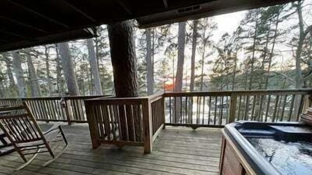A wooden deck with a hot tub, chairs, and a view of a forest. - Mountain Harbor two bedroom Lodge cottage by RedAwning (Mount Ida)
