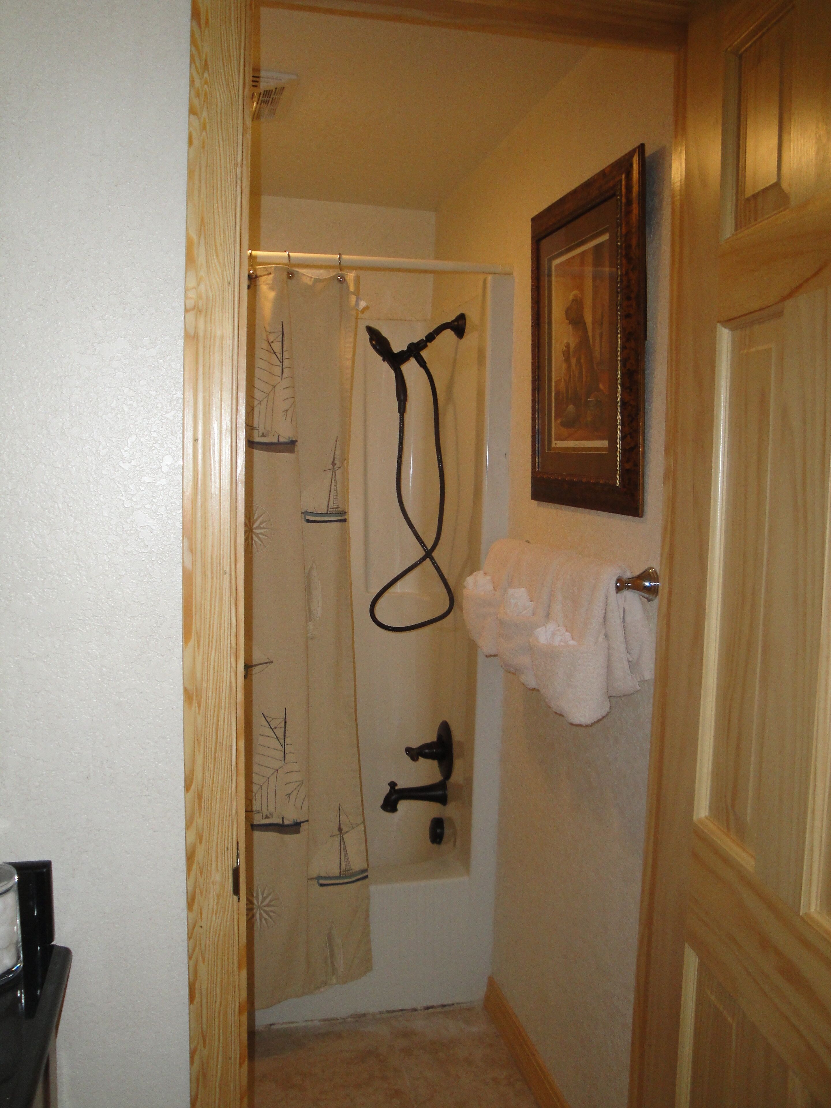 A bathroom with a shower curtain, a towel rack, and a framed picture on the wall.