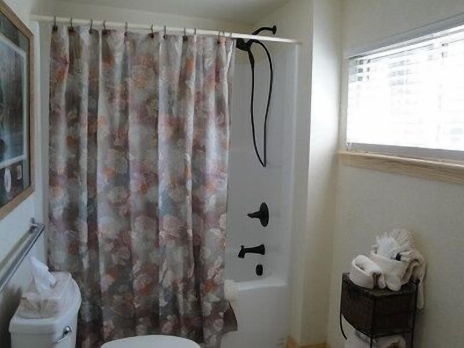 Une salle de bain avec un rideau de douche, des toilettes et une petite étagère avec des serviettes.