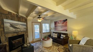 A spacious living room with a stone fireplace, a large painting, and a cozy seating area with a patterned rug. - Mountain Harbor two bedroom Lodge cottage by RedAwning (Mount Ida)
