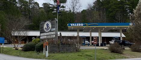 A gas station with a Valero sign, a wooden sign for Mountain Harbor, and a satellite dish.