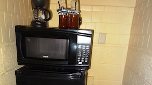 A compact kitchenette with a black refrigerator, a microwave, and a coffee maker.
