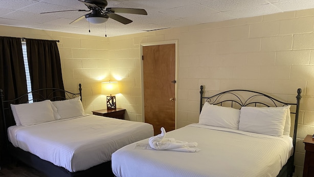 A hotel room with two beds, a wooden floor, a ceiling fan, and a door. - Queen Guest Room located at the Joplin Inn at the entrance to Mountain Harbor, , just 2 1/2 miles from Lake Ouachita. by RedAwning (Mount Ida)