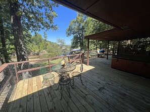 A wooden deck with metal chairs and a table, overlooking a body of water and trees. - Lake side three bedroom, two bath house on Lake Ouachita with private hot tub. by RedAwning (Mount Ida)