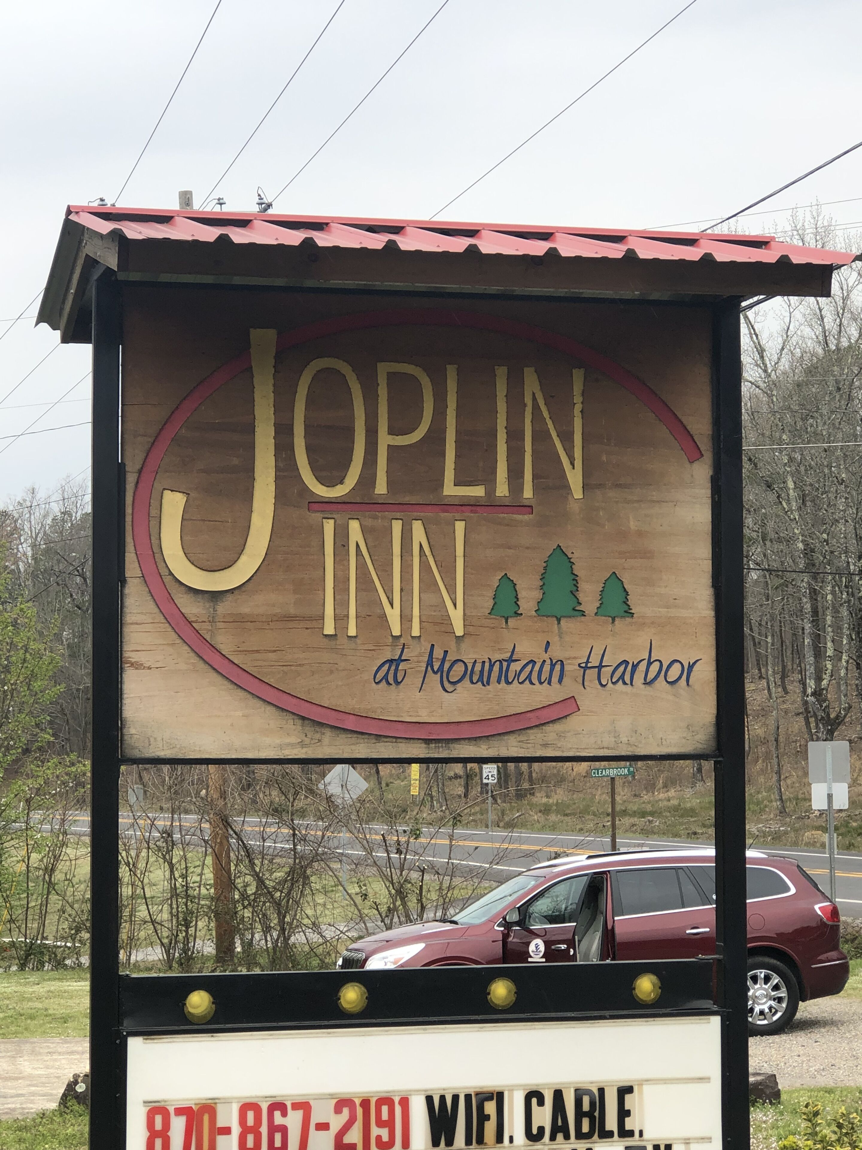 Señal de madera del Joplin Inn en Mountain Harbor, con un número de contacto y la indicación de WIFI y cable.