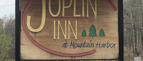 Señal de madera del Joplin Inn en Mountain Harbor, con un número de contacto y la indicación de WIFI y cable.