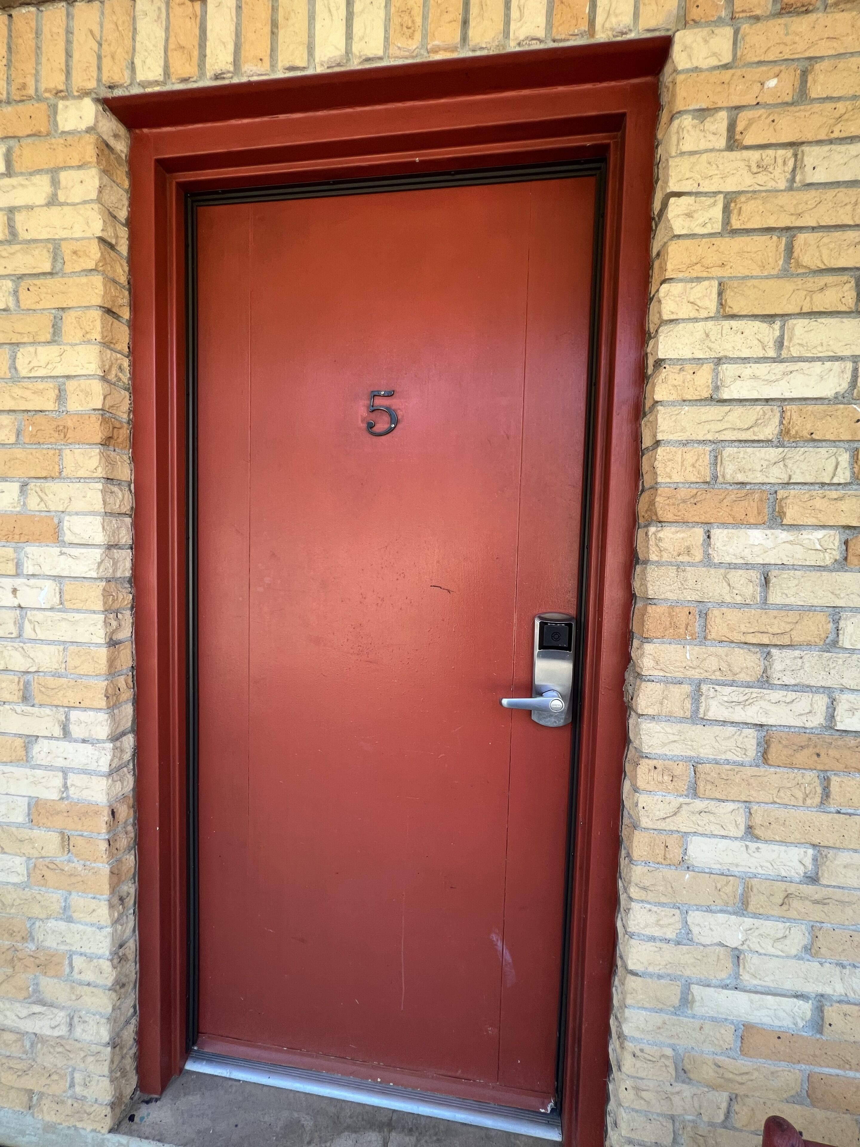 A red door with the number 5, a metal handle, and a keypad lock.