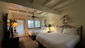 Un dormitorio con dos camas, un ventilador de techo y una mesita de noche con lámpara.