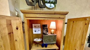 Un moble de fusta amb una cafetera, una làmpada i objectes decoratius als prestatges.