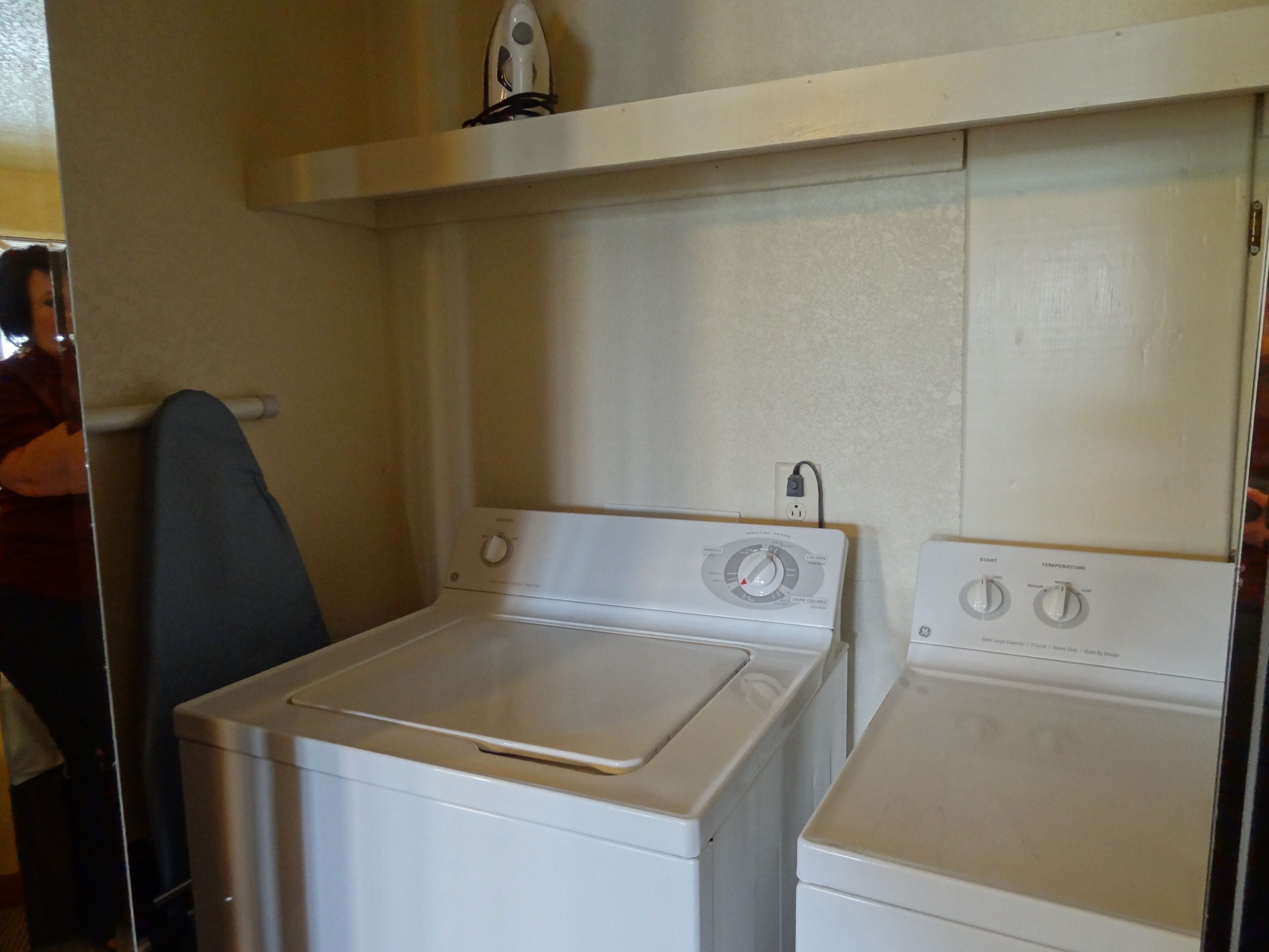 A laundry area with two white washing machines and a dryer.