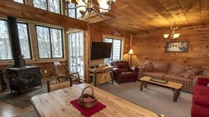 Un interior de cabaña acogedor con una mesa de comedor de madera, un sofá, un televisor y una chimenea.