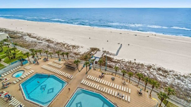 Ein Hotel direkt am Strand mit mehreren Schwimmbecken, Liegestühlen und Blick auf den Ozean.