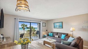 A living room with a sofa, coffee table, and a view of the beach through large windows. - The Summit 307 - Gulf Front Condo with Beach Views (Panama City)