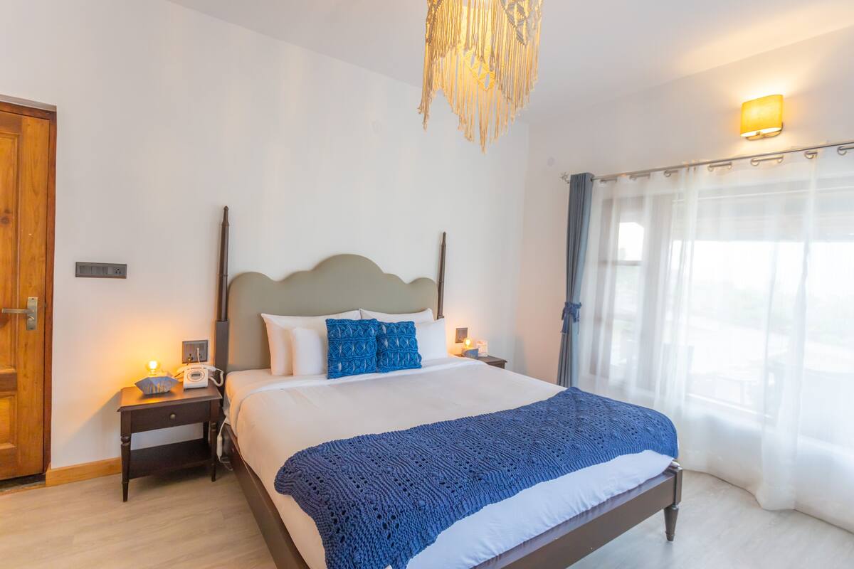 A bedroom with a bed, bedside tables, a lamp, and a window with curtains.