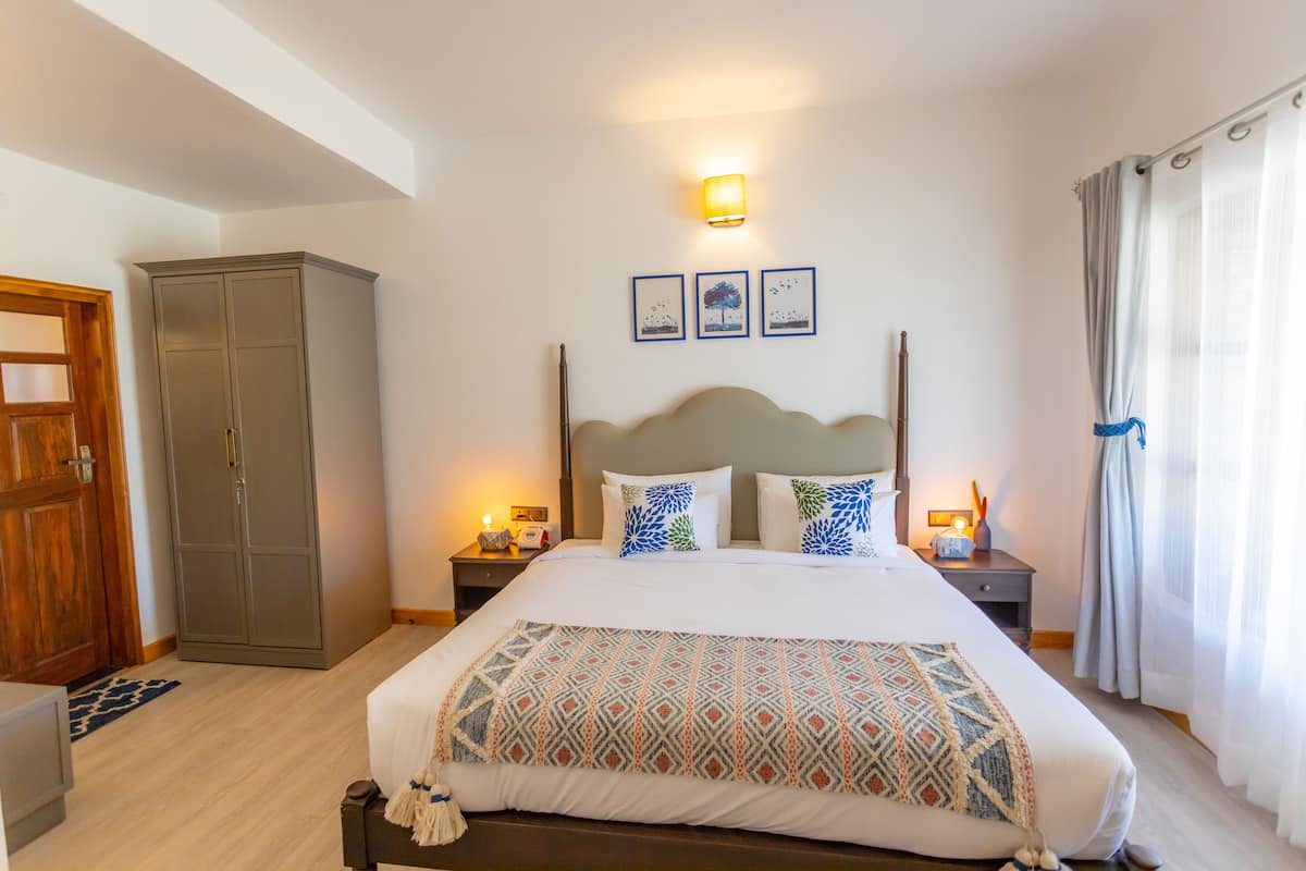 A neatly arranged bedroom with a large bed, a wardrobe, and a bedside table with a lamp.