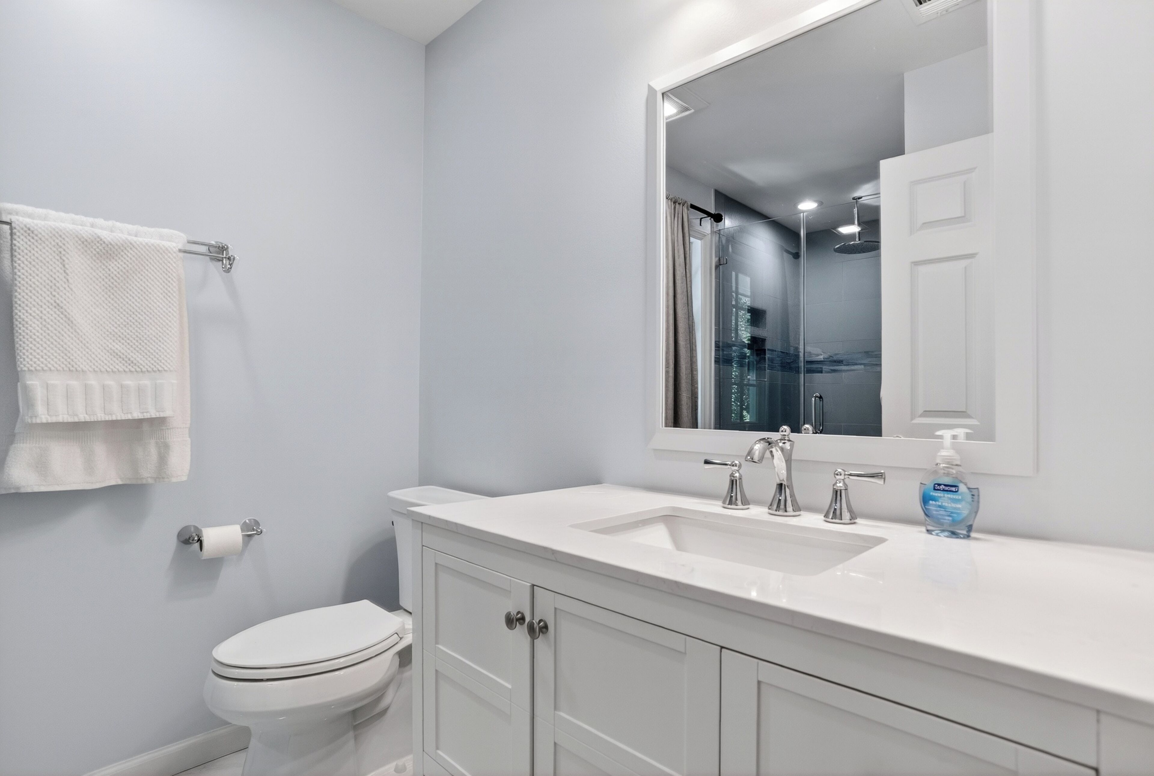 A modern bathroom with a white sink, mirror, and toilet.