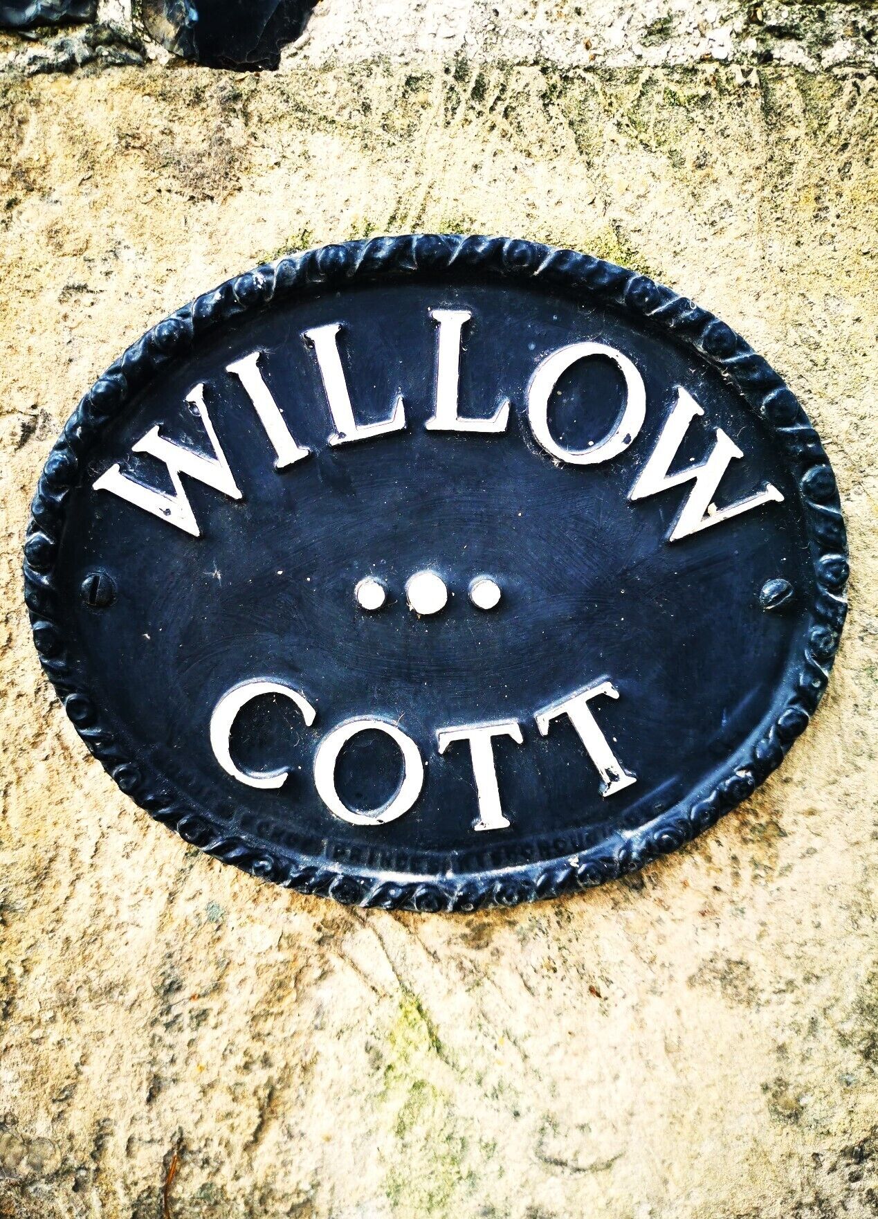 A black metal sign with the words "WILLOW COTT" engraved on it.
