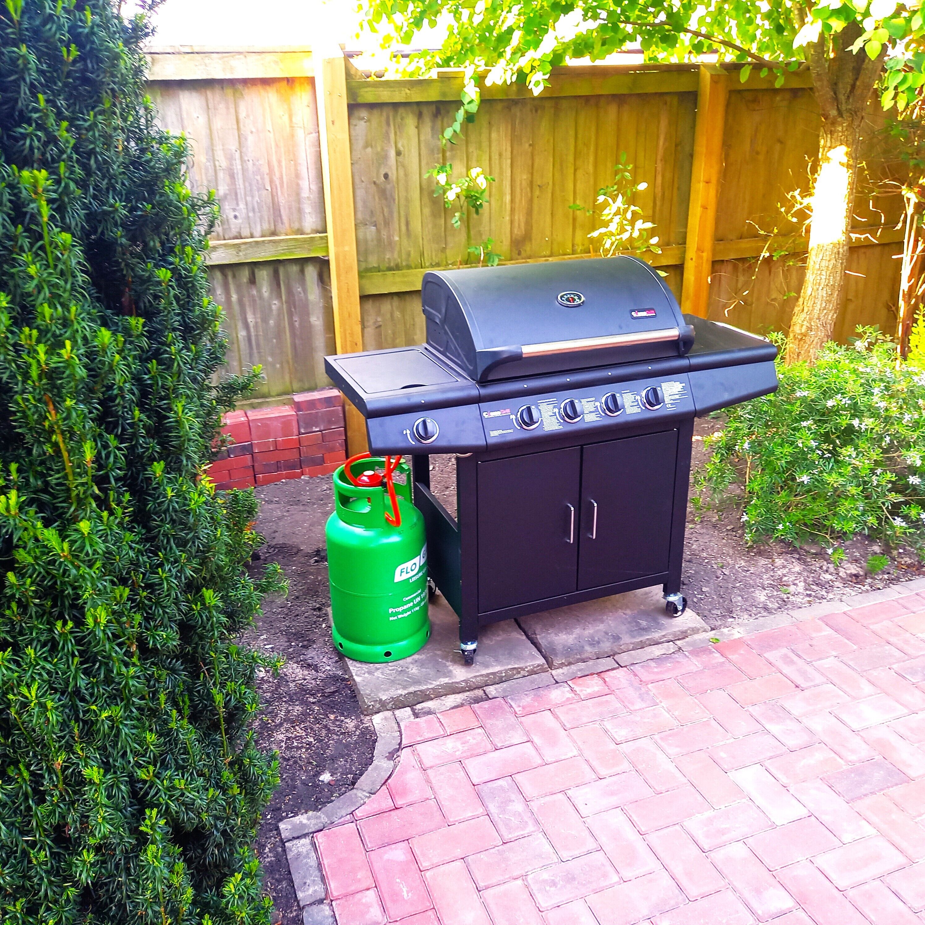 A black barbecue grill with a gas tank beside it.