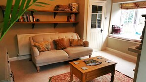 A cozy living room with a sofa, a coffee table, and a bookshelf. - Beautiful, traditional rural cottage (Shrewton)