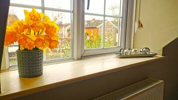 A window with a flower vase and a plate of salt and pepper shakers on the windowsill.