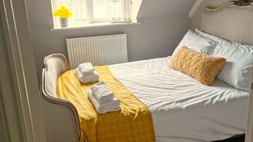A bedroom with a bed, a window with a view, a radiator, and a yellow throw blanket.
