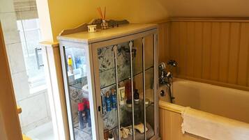 A bathroom with a glass-fronted cabinet, a bathtub, and a yellow wall.