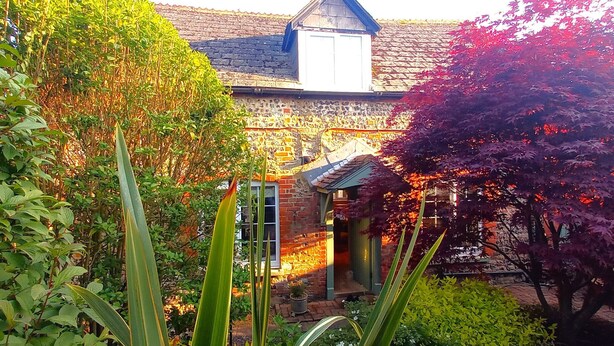 A traditional brick house with a gabled roof, surrounded by lush greenery and flowering plants. - Beautiful, traditional rural cottage (Shrewton)