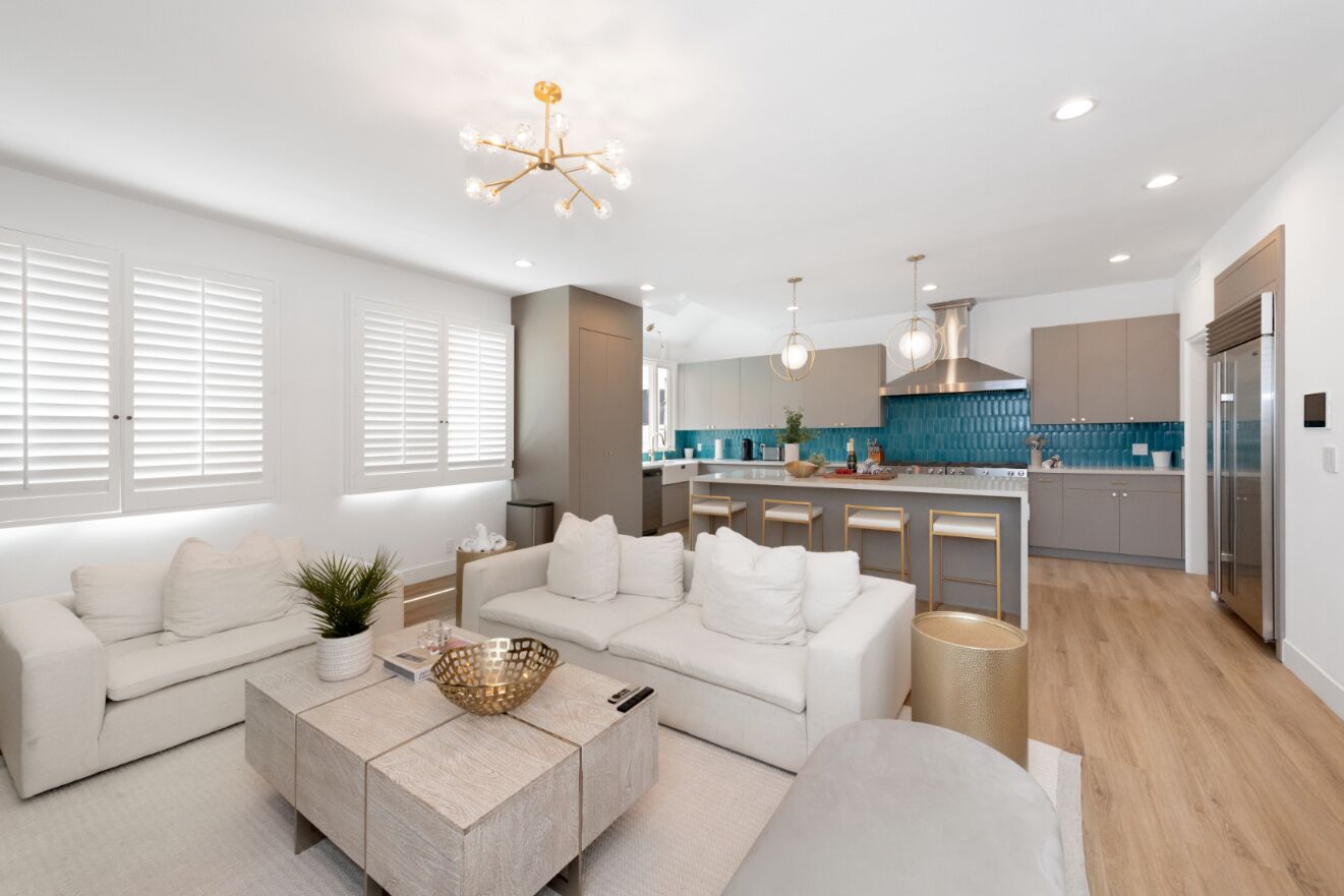 A modern living room with a sofa, coffee table, and a kitchen in the background.