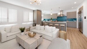 Ein modernes Wohnzimmer mit Sofa, Couchtisch und einer Küche im Hintergrund.