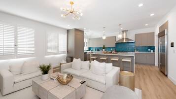 A modern living room with a sofa, coffee table, and a kitchen in the background.