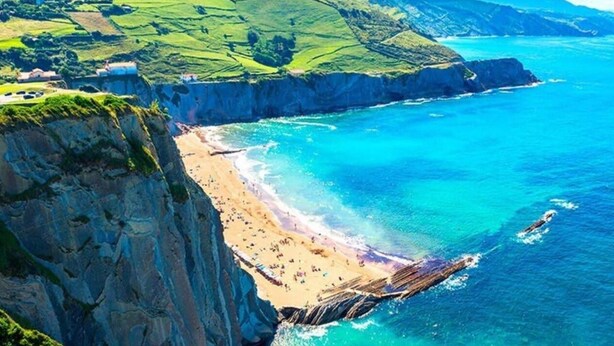 Eine Küstenlandschaft mit Klippe, Strand und Meer.