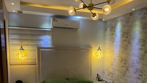 Een moderne slaapkamer met een groot bed, een nachtkastje, een wandairconditioner en een bijzondere lamp.
