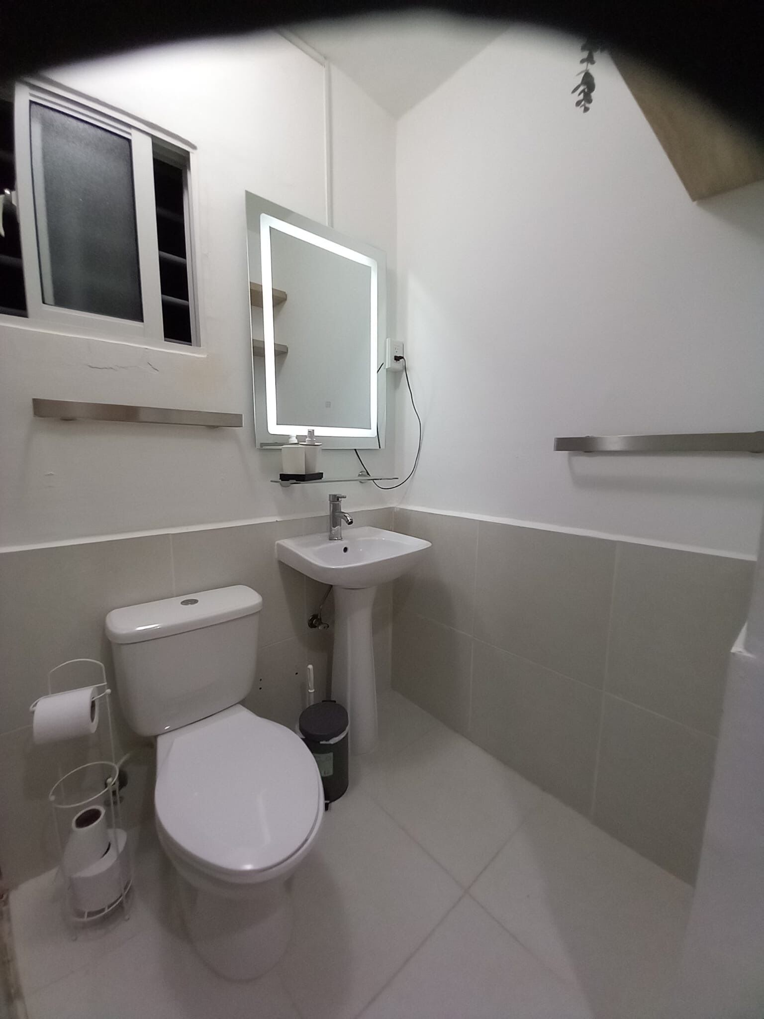 Een kleine, witte badkamer met toilet, wastafel en spiegel.