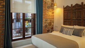 Una camera da letto con un letto grande, un muro in pietra, una finestra con tende e un pannello decorativo in legno.