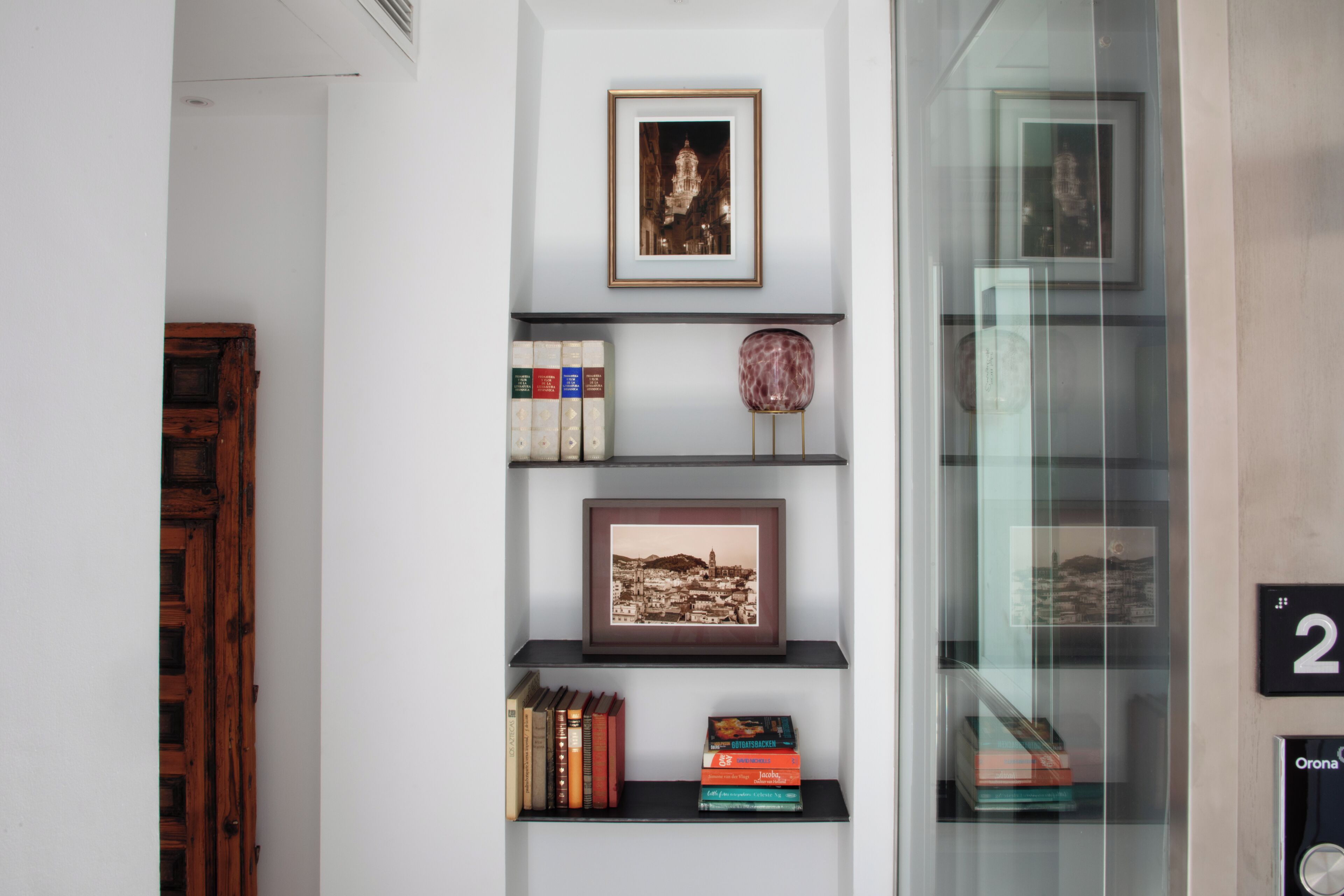A bookshelf with framed pictures, books, and decorative items.
