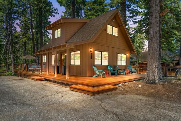 Une cabane en rondins à deux étages, dotée d’une terrasse, de grandes fenêtres et de meubles pour s’asseoir à l’extérieur.