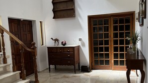 Een ruime kamer met een marmeren vloer, een houten trap, een houten dressoir en een groot raam met uitzicht.