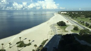A beach with a long stretch of sand, a pier extending into the water, and a road running parallel to the beach. - Magnolia Beach House l Brand NEW AC UNIT (Gulfport)