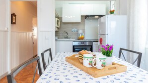 Un'area pranzo con un tavolo apparecchiato per due, una cucina sullo sfondo e una sveglia al muro.