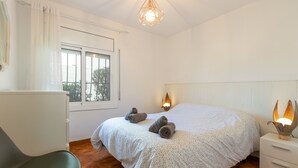 Una camera da letto con un letto, due abat-jour, una sedia, una finestra e un comodino.