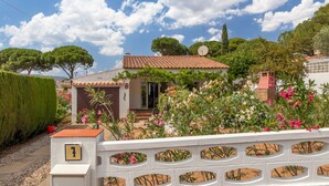 A house with a tiled roof, a satellite dish, and a garden with various plants and flowers. - Holiday Home 'Giovanni' with Shared Terrace and Wi-Fi (L'Escala)