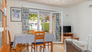 A dining area with a table and chairs, a television, and a sofa. - Holiday Home 'Giovanni' with Shared Terrace and Wi-Fi (L'Escala)