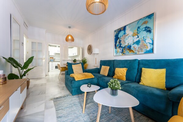 A living room with a blue sofa, a white coffee table, a blue rug, and a large abstract painting on the wall. - Holiday Apartment "Doña Sofía" with Sea View, Private Terraces & Wi-Fi (Fuengirola)